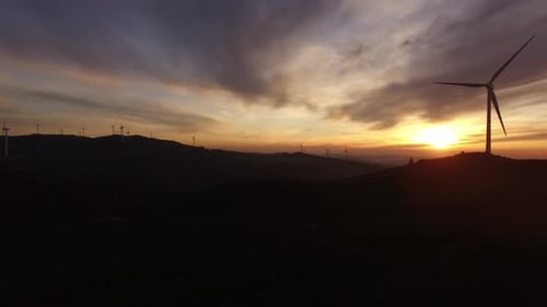 Renewable clean energy from wind farm with windmills. Aerial drone shot of wind turbines at sunset