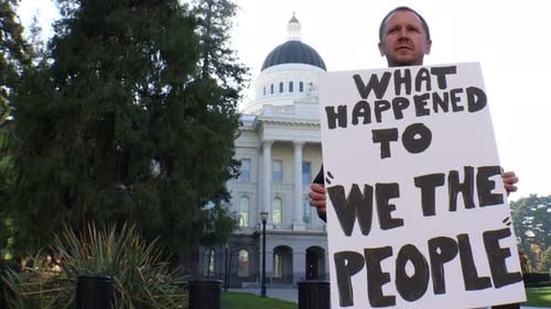 Man Holds Protest Sign Outside Government Building