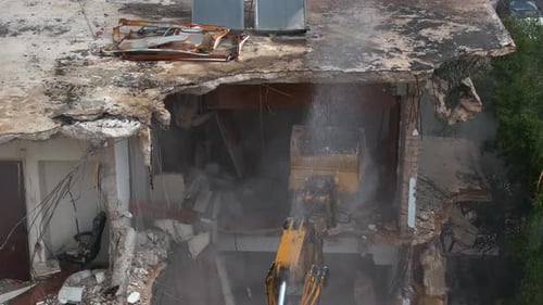 Building demolition excavator using Pulverizer Jaws to demolish a residential building