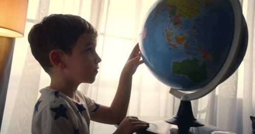 Child is Studying While Sitting at Home in Rays of Sun in Room