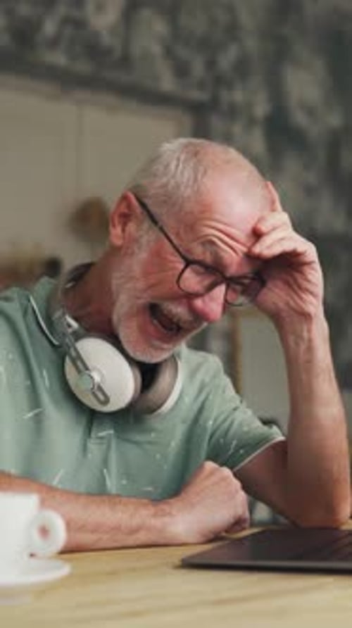 Senior Man Reacting to Laptop in Home Setting