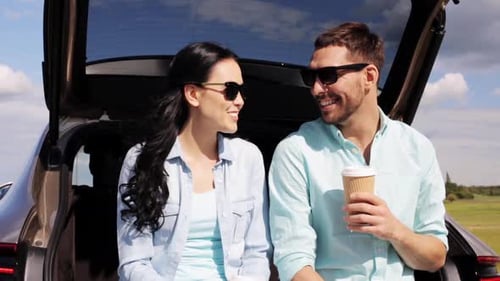 Happy hispanic couple enjoying coffee on a summer road trip in their hatchback