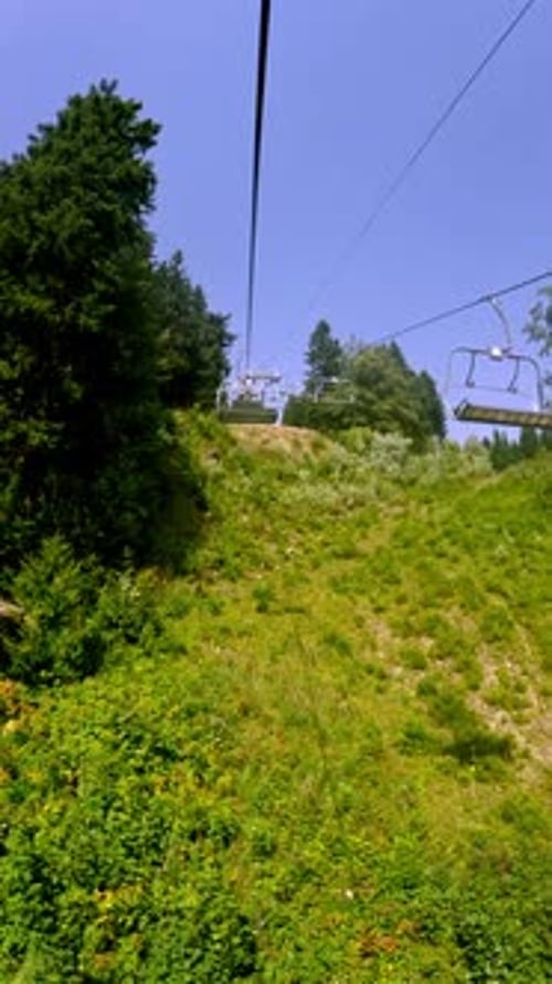 Vertical Timelapse of a Chairlift Ride Going Up a Green Mountain Slope