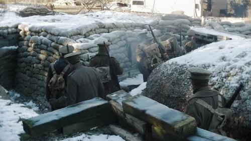 A snow covered First World War tench, cold British WW1 army soldiers walk back from the front line i