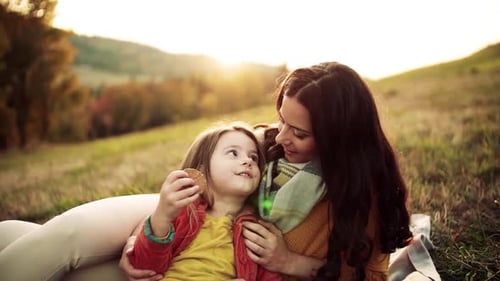 Mother and Child Relaxing on Blanket at Sunset