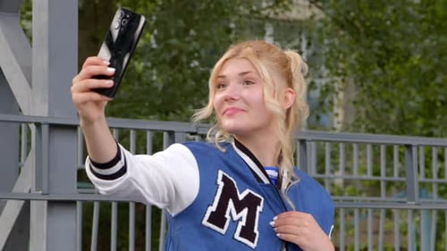 Smiling Woman Takes Selfie with Mobile Phone Outdoors