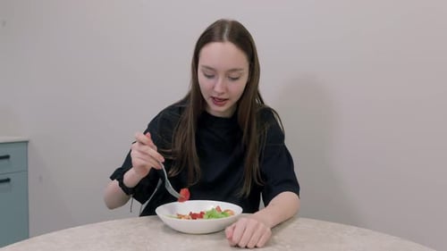 Young Woman Eating Healthy Salad At Home