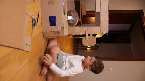 Vídeo vertical Boy construye un coche con cartón reciclando cartón usado