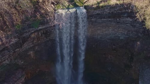Majestic waterfall cascading down a rugged cliff surrounded by nature