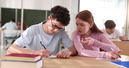 Students taking test at wooden desk in classroom