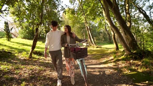 Young couple walking with bicycle in park