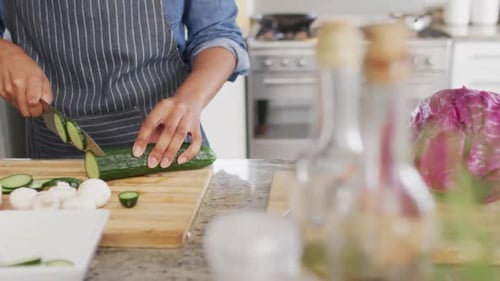 Video of midsection of caucasian man cutting cucumber in kitchen