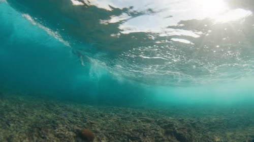 Underwater view of the ocean wave breaking on the shore during sunset light in the Maldives