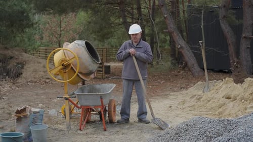 An Elderly Construction Worker Resting with a Shovel