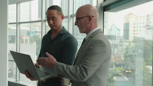 CEO and Manager Analyzing Statistics Using Laptop at Office