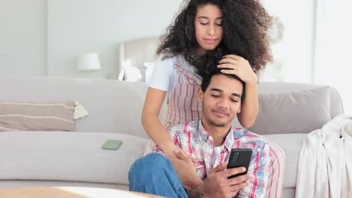 Man with Woman Embracing While Using Smartphone