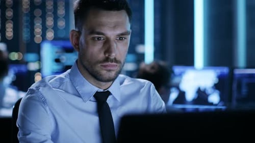 Primer plano de un controlador técnico profesional sentado en su escritorio con varias pantallas ante H