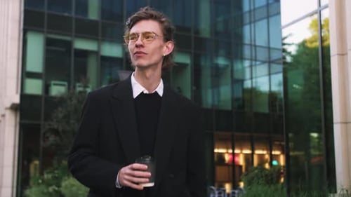 Kaukasischer gutaussehender eleganter Geschäftsmann in Anzug und Brille geht in die Nähe eines modernen Büros, um darin zu arbeiten