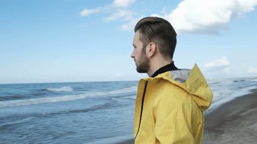 The Picture Of Enjoyment Adult Stylish Hipster In Coat Walk On The Wild Empty Seaboard Close Up. ...