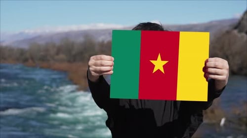 Person Holding Cameroon Flag by River