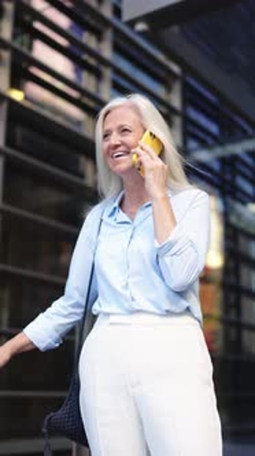 Mature Professional Talks on Mobile in Vertical View with Urban Backdrop Finance and Business