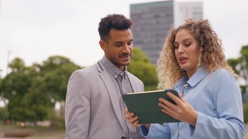 Colleagues Discussing Work Using Tablet in Urban Setting