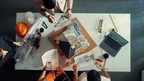 Top view of manager handed blueprint to engineer at meeting table. Alimentation.