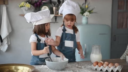 Two kids in white chef uniform mixing flour in bowl and adding milk on the kitchen