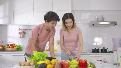 Pareja de jóvenes asiáticos que preparan vegetarianos, beben un batido fresco y sonríen, disfrutan de la vida.