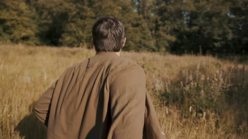 POV: A young man is running and holding someone's hand, leading them through a tall grass field.