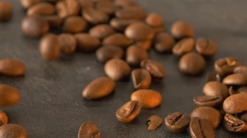 Close-up of fresh coffee beans falling on a brown rustic table ready to grind and prepare