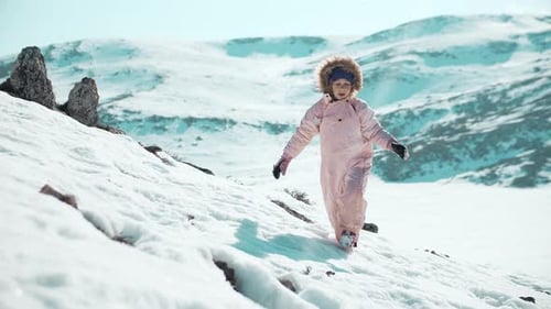 Child Climbing Snow Covered Mountain in Winter