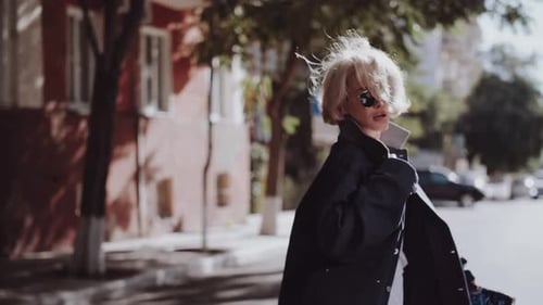 An Attractive Young Woman in a Blue Coat Walks Girl Walking in the City