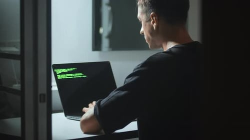 Man Working on Laptop with Code at Night