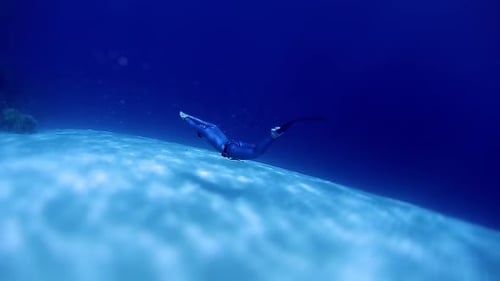 Diver Swimming Underwater in Blue Ocean