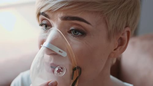 Femme malade respirant à travers un masque inhalateur ayant une maladie respiratoire à l'intérieur