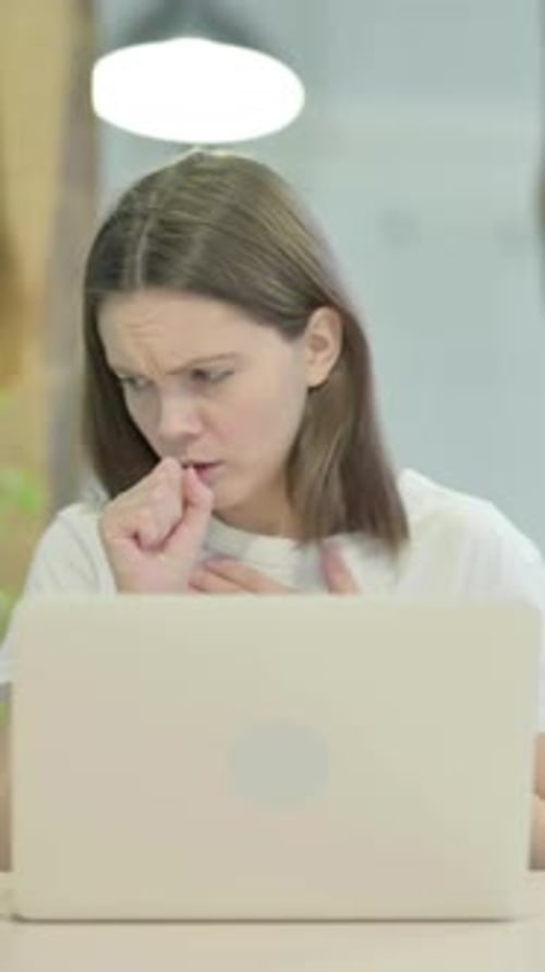 Sick Young Woman Coughing While Working on Laptop
