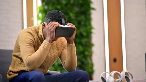 A black man putting on VR glasses in an office and starts exploring virtual reality
