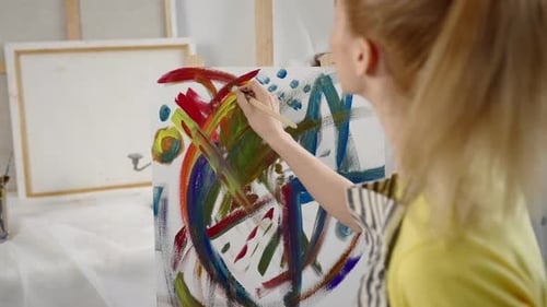 Studentin der Kunstschule zeichnet abstraktes Bild auf Staffelei im Workshop Talentierte Künstlerin