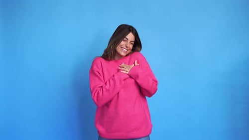 Cheerful Young Woman Showing Heart Gesture in Studio