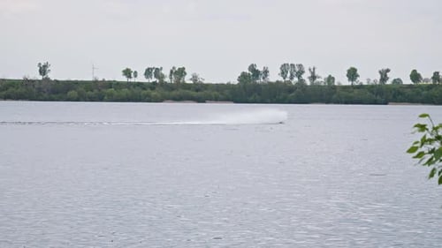 A Speedboat Maneuvering Through the Lake, Creating a Splash of White Water in its Wake - Wide Shot