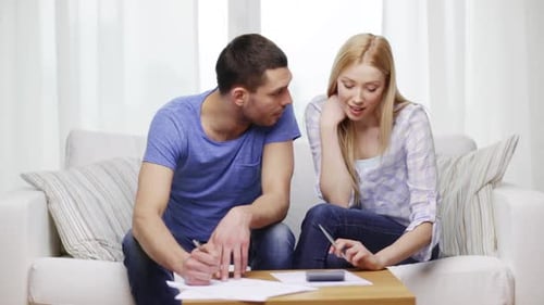 Couple Sitting on Couch Reviewing Documents Together