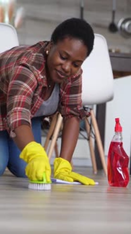 Housekeeper scrubbing floor with brush and detergent