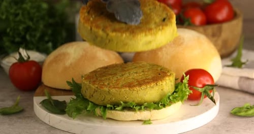 Woman making vegan burger with plant-based patties at light table, closeup