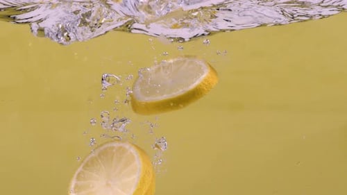 Lemon Slices Splashing into Clear Water