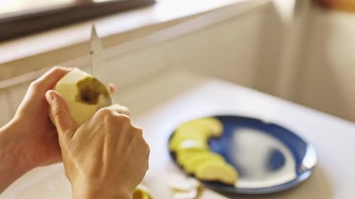 Peeling an Apple with a Knife in Kitchen
