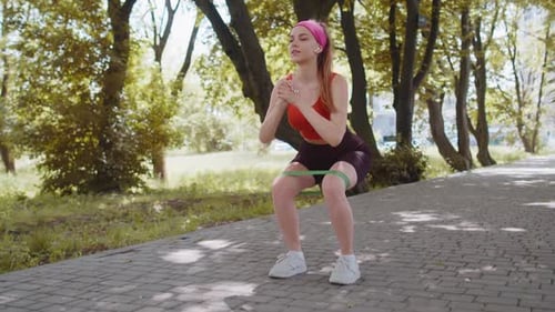 Athletic Fit Sport Girl Doing Squats Using Fitness Elastic Rubber Band Workout Outdoors Sunny Park