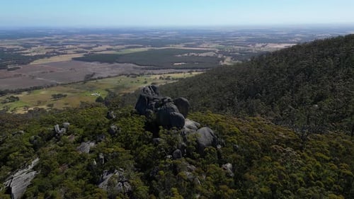 Orbitre aérienne d'un belvédère rocheux dans la brousse australienne, terres agricoles en arrière-plan