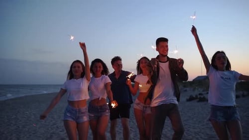 Friends Walking Dancing Having Fun at Night Party at the Seaside with Sparklers in Their Hands Young