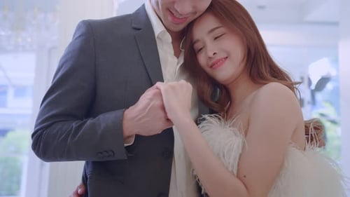 Asian beautiful bride trying on wedding gown with her fiance in studio.